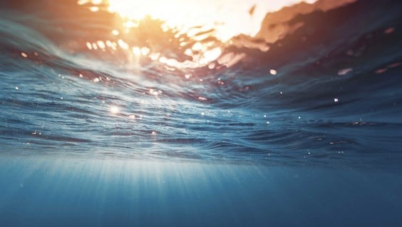 Solljus som lyser ner genom vattenytan.