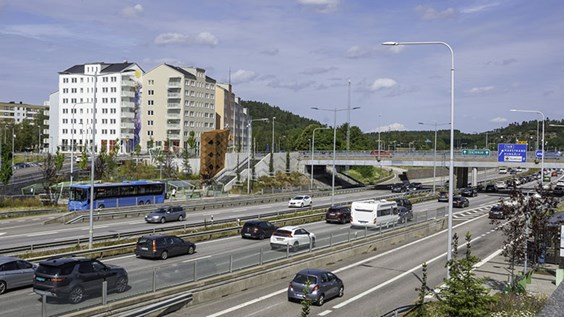 Bilar som kör på E6, bostadshus i bakgrunden.