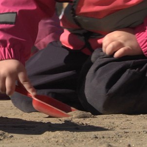 Barn gräver med plastspade i sandlådan